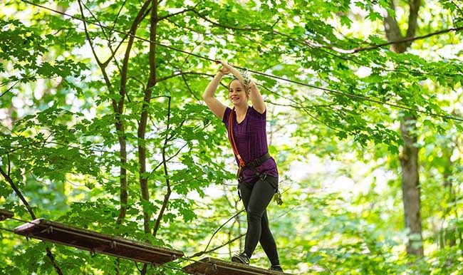 femme sur un parcours hébertisme entre les arbres