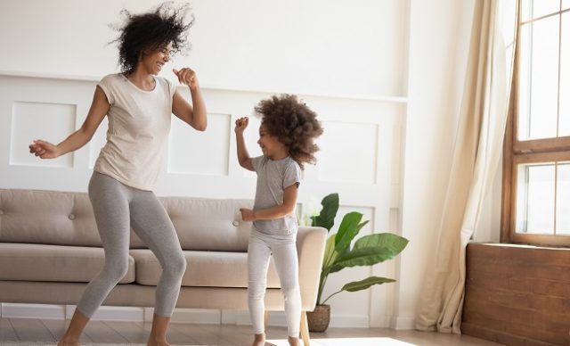 une mère et sa fllle dansent dans le salon