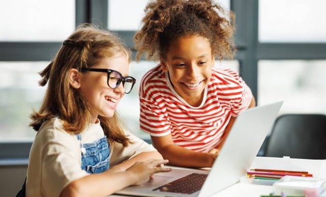 Des écolières regardant l’écran de l’ordinateur portable en classe