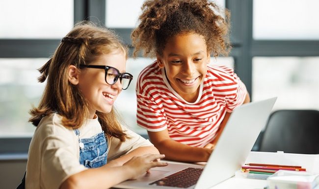 Des écolières regardant l’écran de l’ordinateur portable en classe