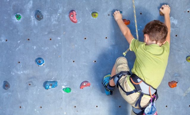 garcon qui grimpre a mur escalade intérieur