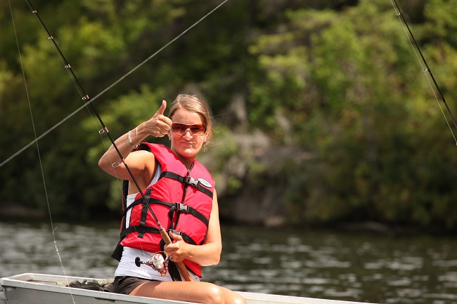 Femme qui pratique la pêche assise dans une chaloupe