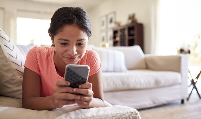 jeune fille qui regarde son cellulaire en souriant